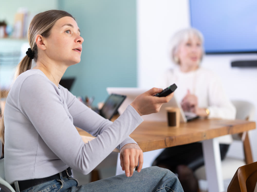 Two female colleagues are watching presentation in office room.