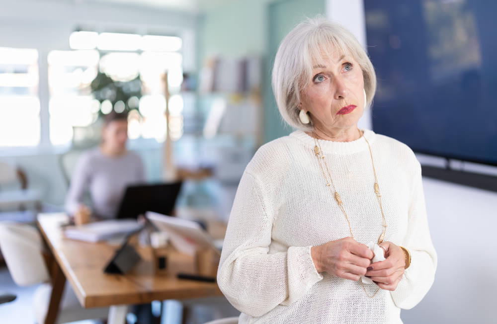 Sad mature woman staff stands in office