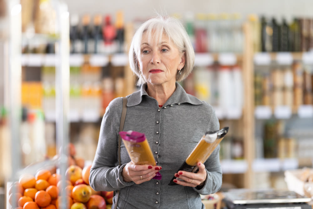 Elderly woman chooses tasty italian pasta to buy in the grocery department section of store