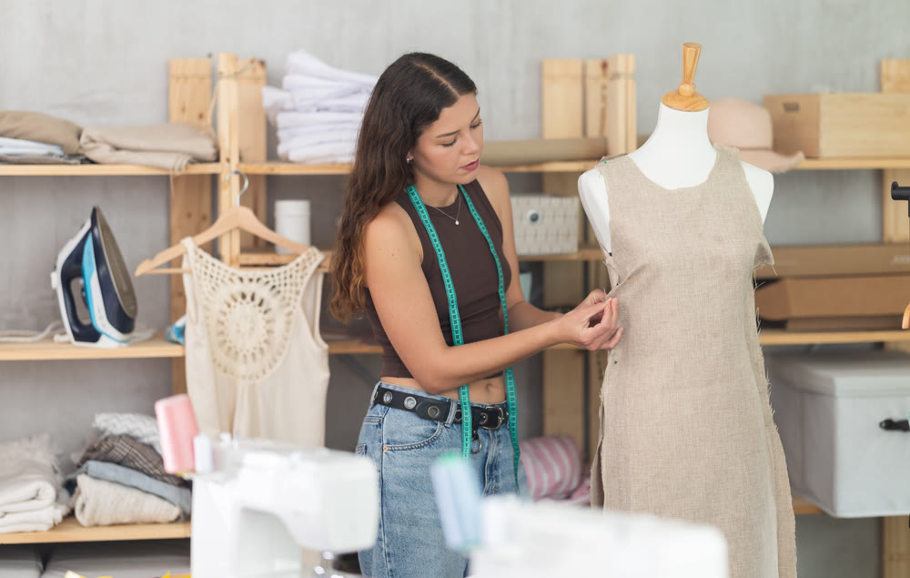 Fashion designer fitting dress on mannequin in dressmaker studio