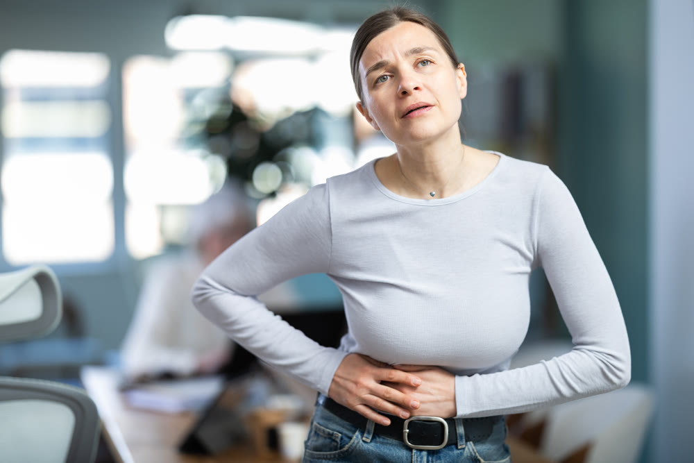 Adult woman with stomach pain during workday in office