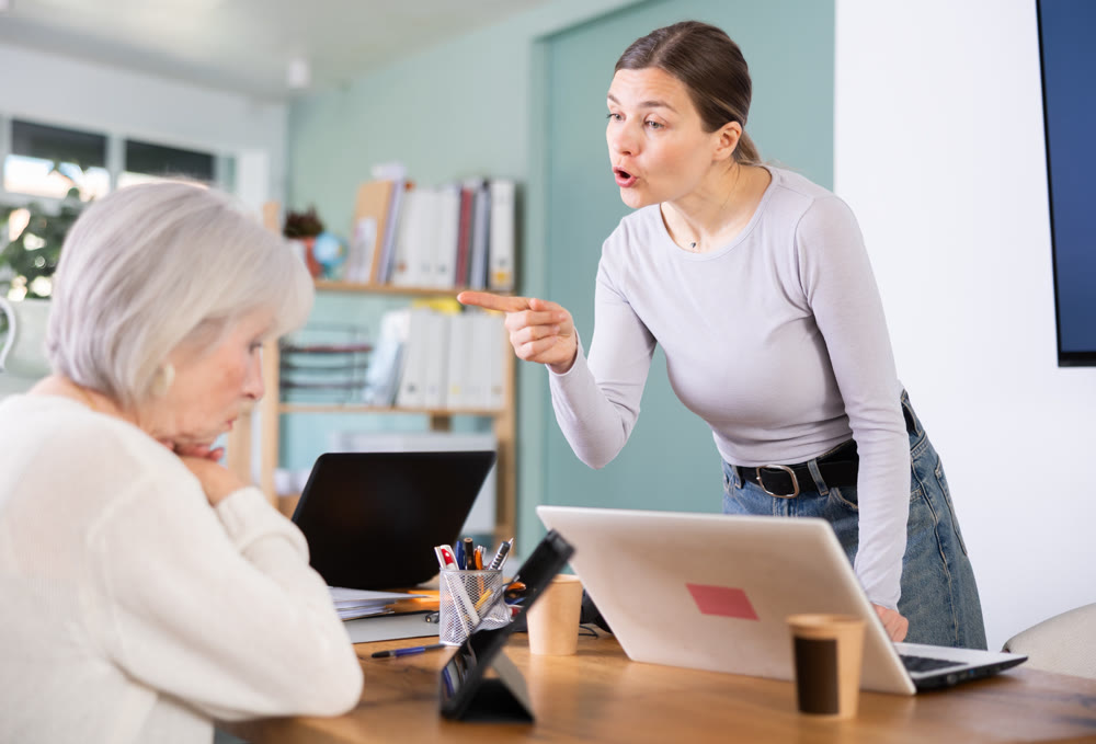 Female boss yells at senior woman employee, pensioner work at tablet