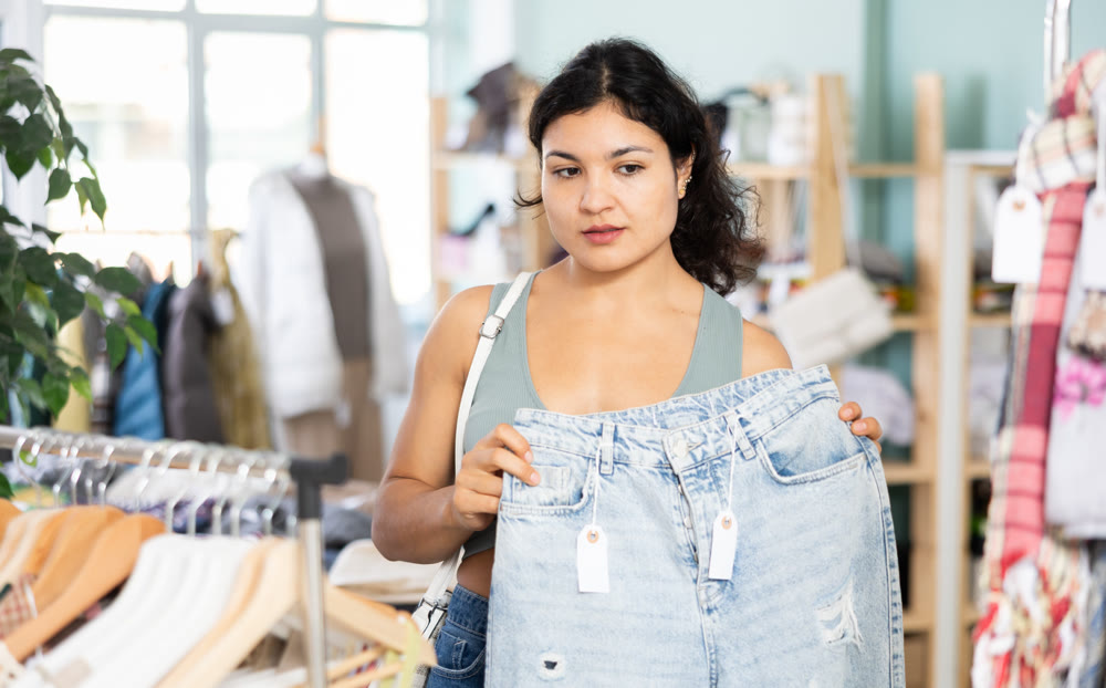 Undetermined young girl choosing jeans pantaloons in clothing store