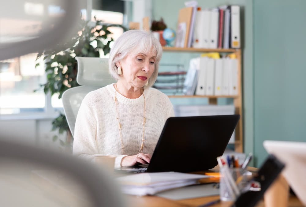 Elderly businesswoman, senior manager, work on laptop in modern company office