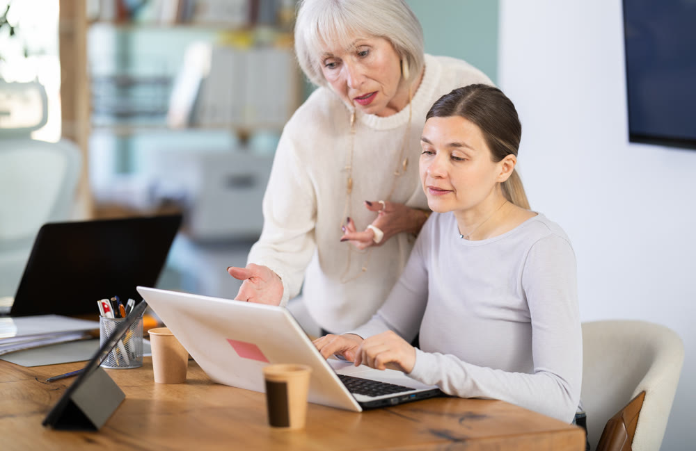 Elderly man help young woman with laptop