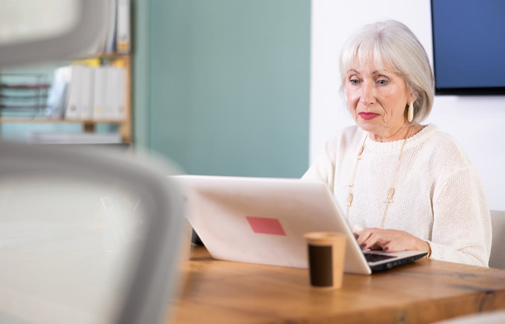 Elderly businesswoman, senior manager, work on laptop in modern company office
