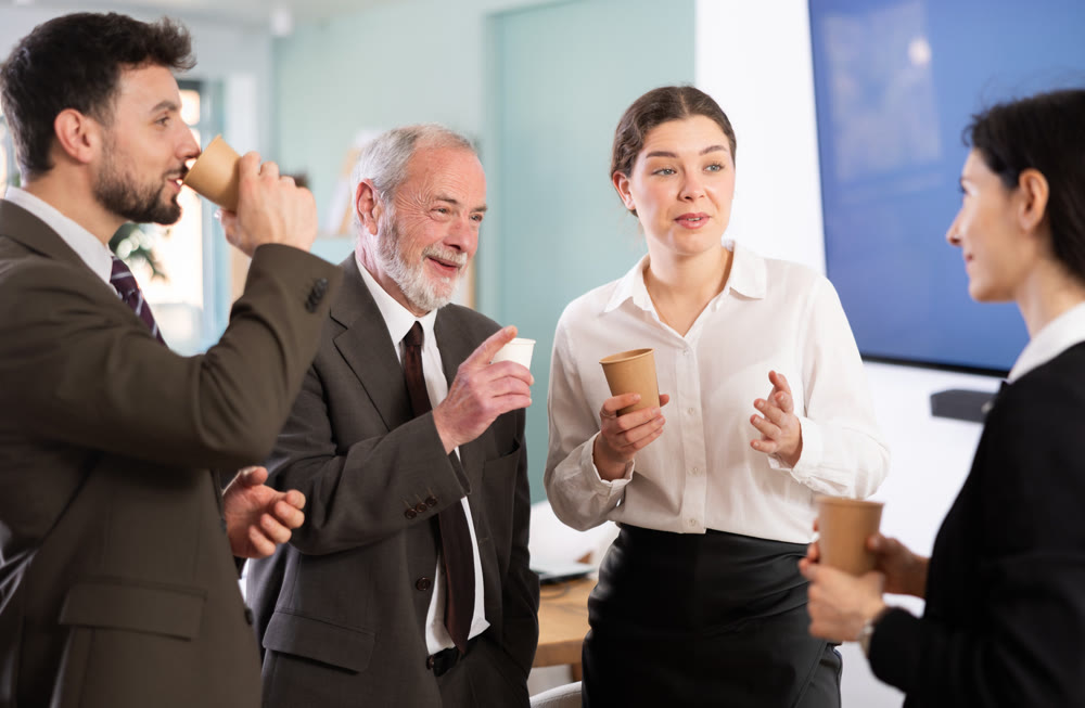 Coffee break - group of office workers drinking coffee and chatting with each other during break