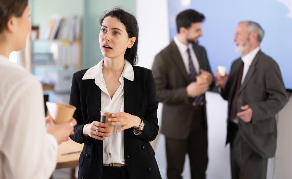 Two girls colleagues chat and laugh during coffee break