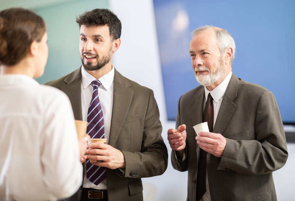 Girl with two men colleagues chat and laugh during coffee break