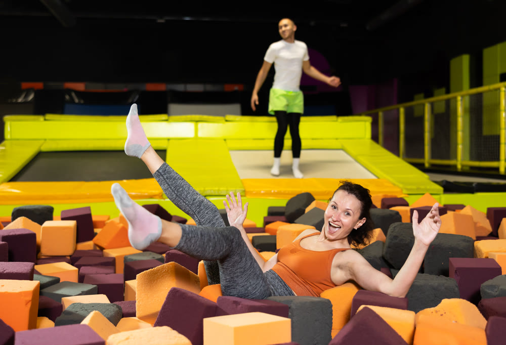 Woman laughing while landing in foam pit at trampoline park