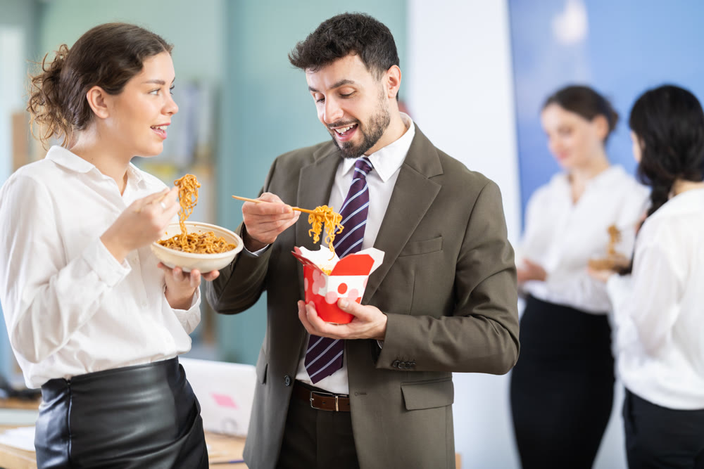 Man and woman office workers resting on break together eating and talking