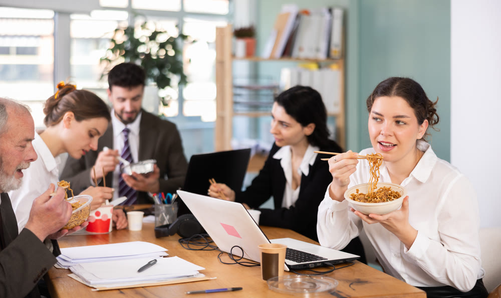 Young female companys employees eat instant noodles, lunch time during break for staff