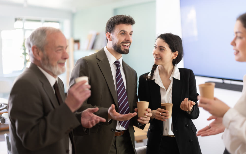Coffee break - group of office workers drinking coffee and chatting with each other during break