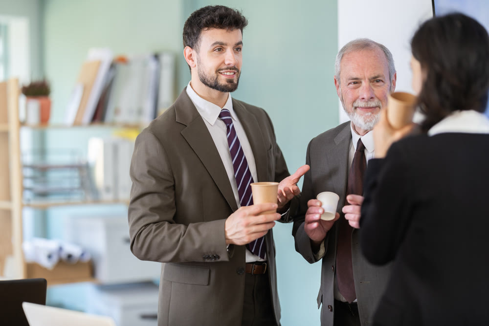 Girl with two men colleagues chat and laugh during coffee break
