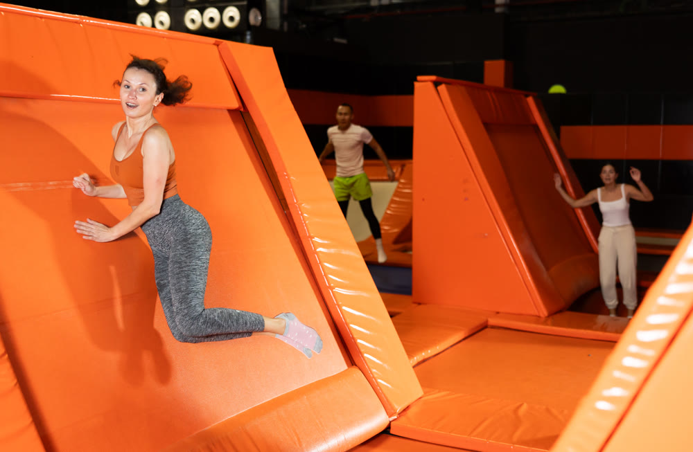 Emotional woman pushing off from angled surface in trampoline park