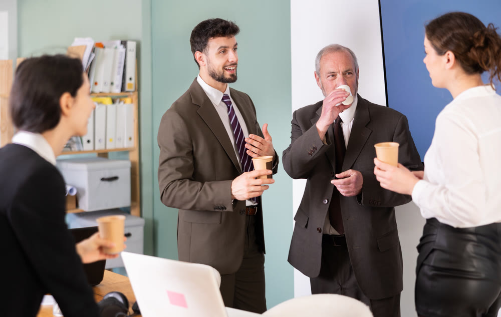 Coffee break - group of office workers drinking coffee and chatting with each other during break