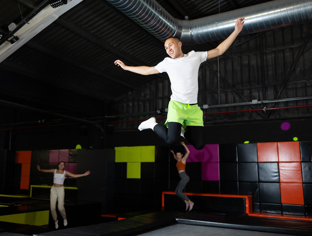 Emotional man jumping vertical and flying in trampoline sport center indoors