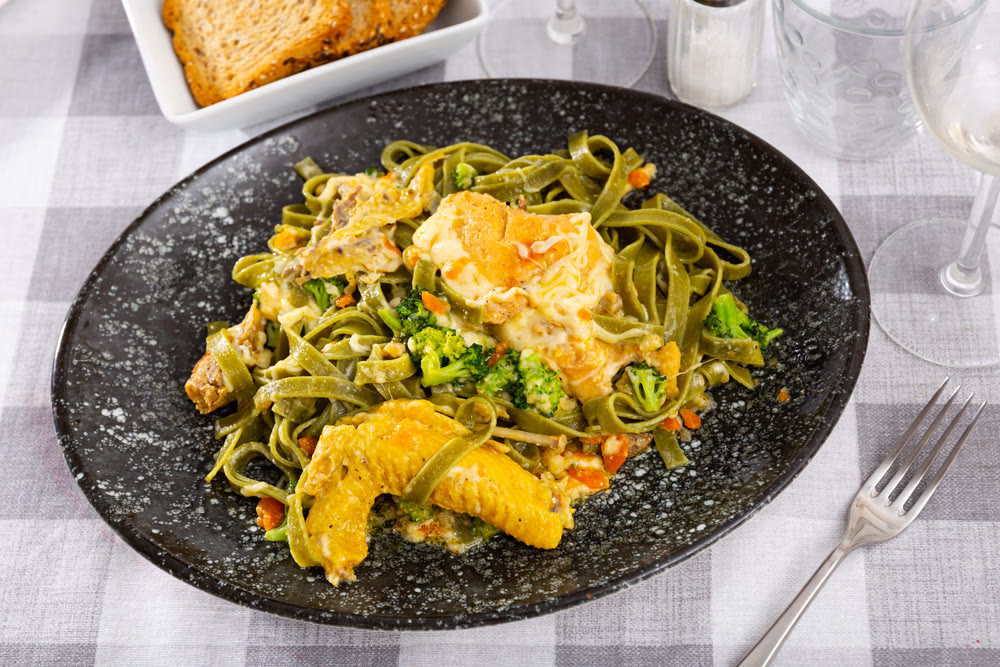 Authentic Italian fettuccine pasta dish with chicken breast and broccoli on table