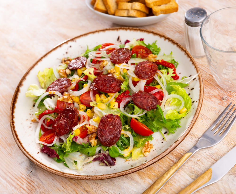 Vitamin salad of fresh vegetables, lettuce leaf, corn, bel pepper and chorizo.