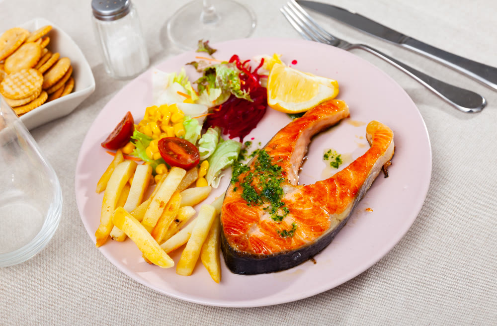 Salmon served with potatoes and vegetable salad