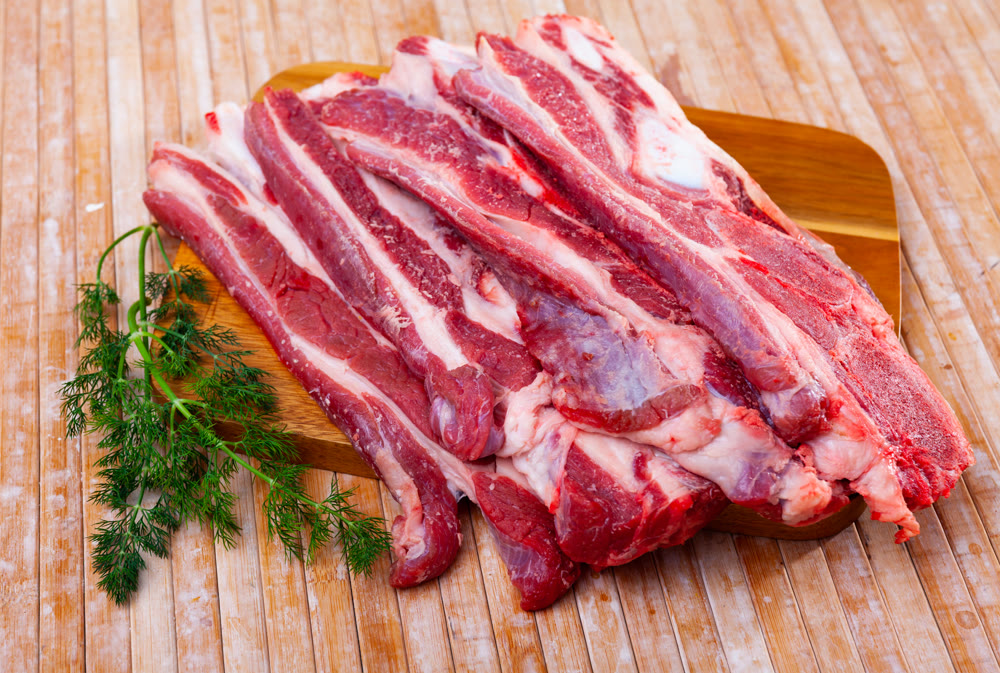 Raw meaty veal tenderloin on plate with fresh dill ready for cooking, closeup