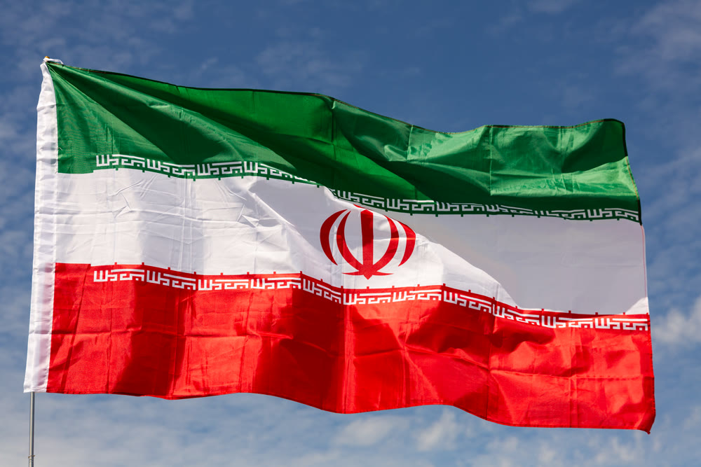 Flag of Iran waving on cloudy sky during daytime
