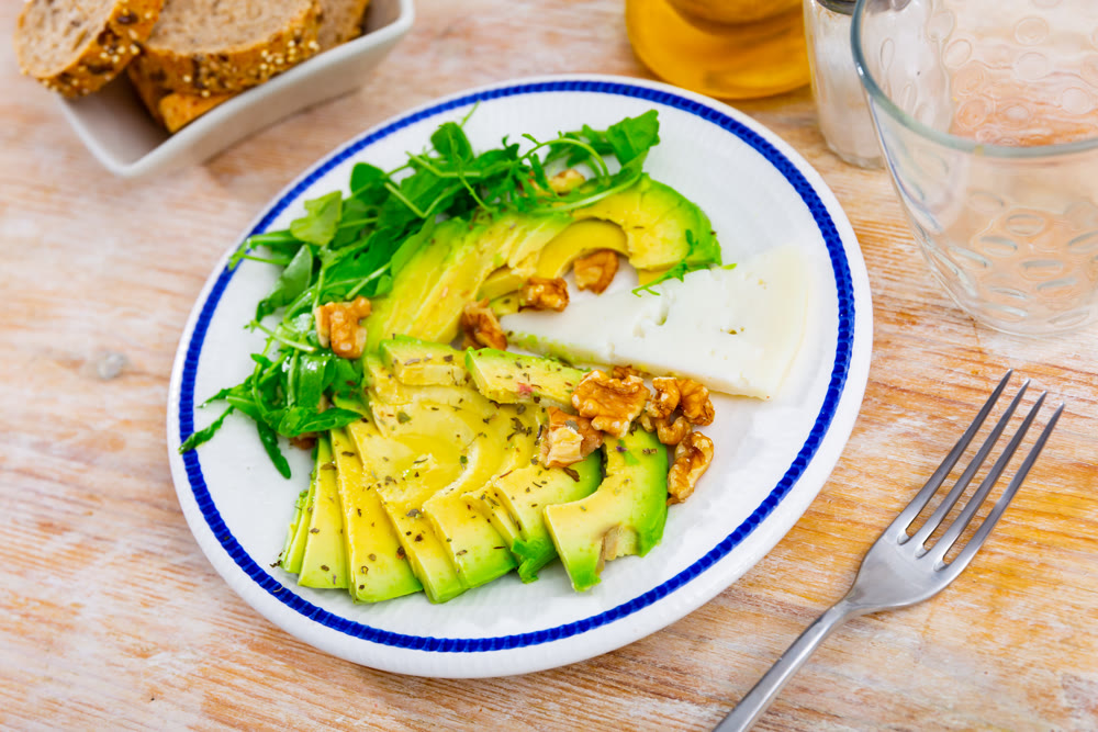 Avocado and cheese served with arugula and walnuts