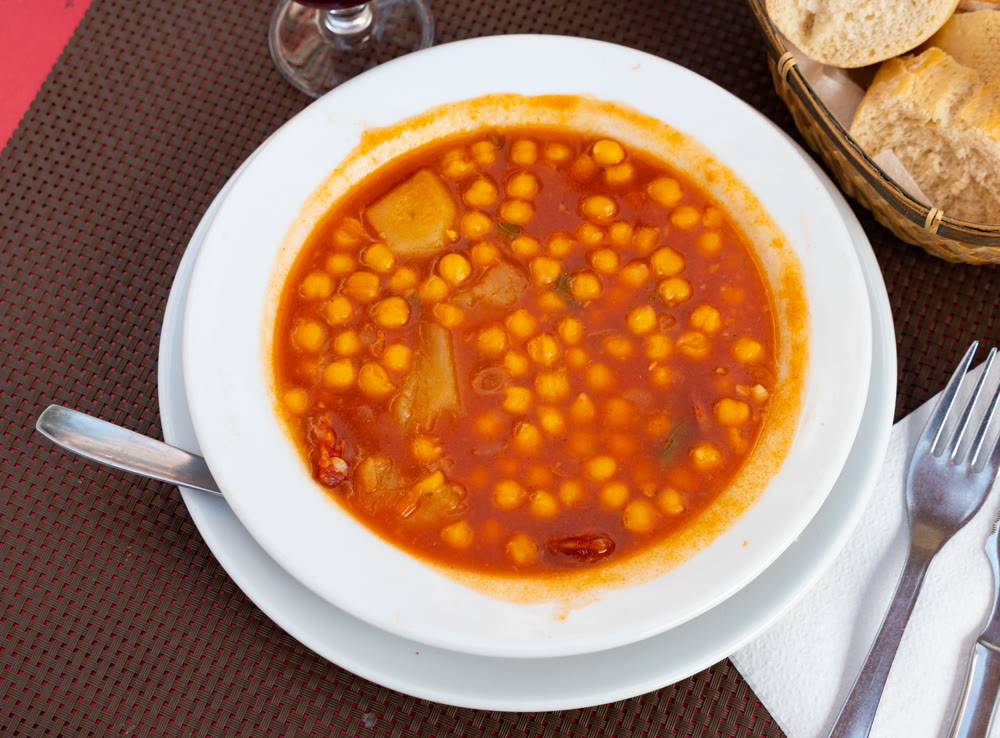 Delicious chickpeas cooked with pieces of chorizo sausage and bacon, onions, garlic, tomatoes, sweet paprika and spices served at plate for dinner. Spanish cuisine Garbanzos con chorizo