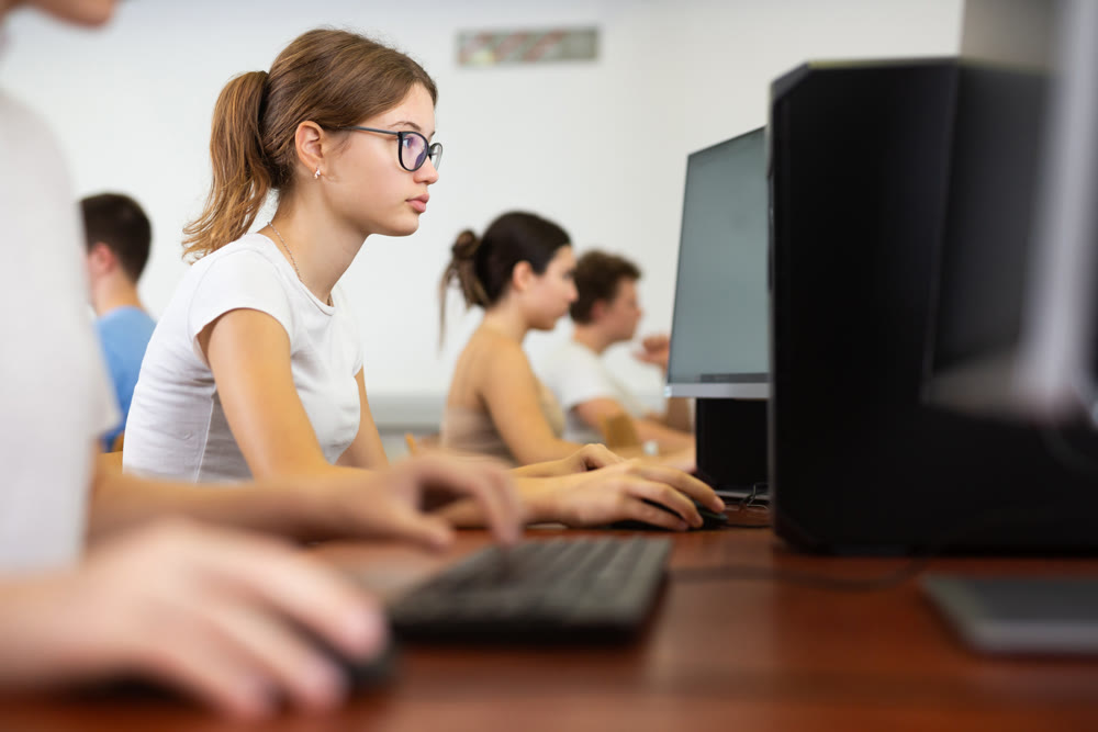 Teenage girl learning to use personal computer during lesson