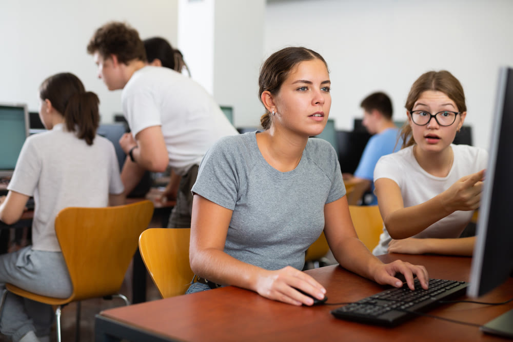 Smart female teenager learning computer science while she is using a PC in the computer classroom