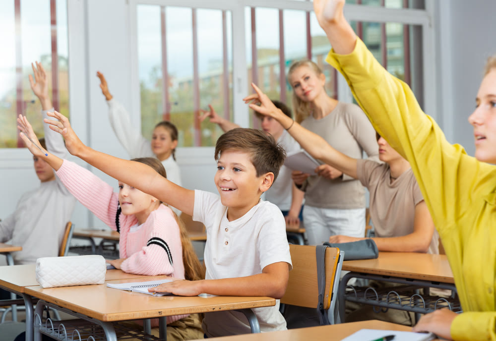 Students raise their hand to answer during lesson in class