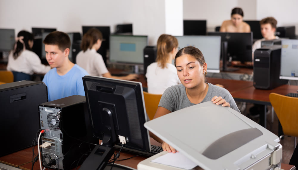 Female teacher uses a scanner in computer lab at school