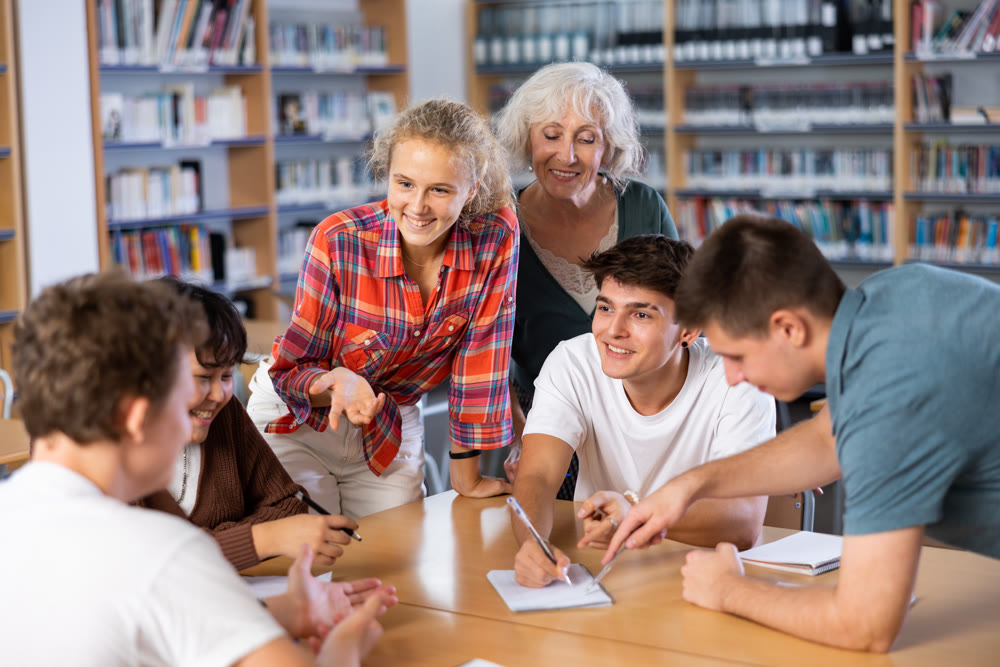 Classmates have fun chatting and telling each other in school library