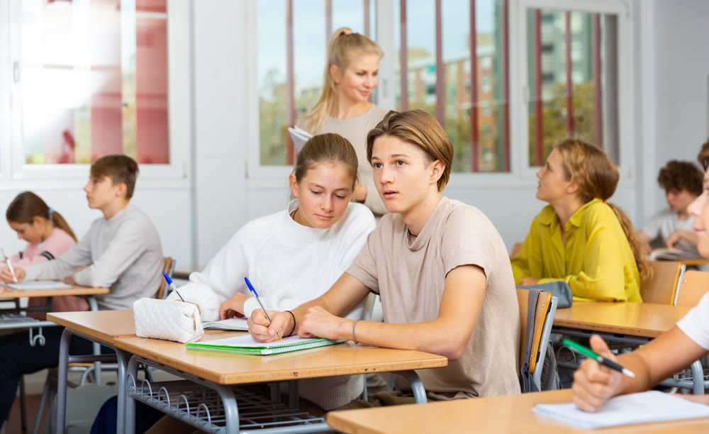 Teenage girls and boys exercising during lesson in school