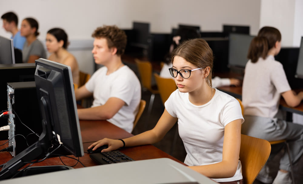 Young girl student with glasses studying on computer in library, concept of education
