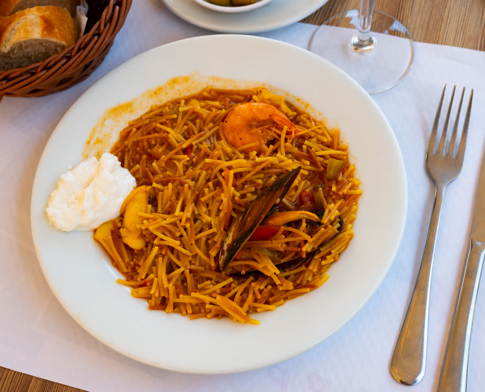 Traditional spanish seafood dish fideua with aioli sauce in restaurant