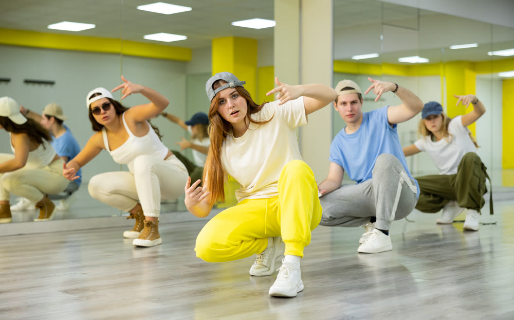 Teenage girls and boys having group dance training in studio, performing dynamic elements