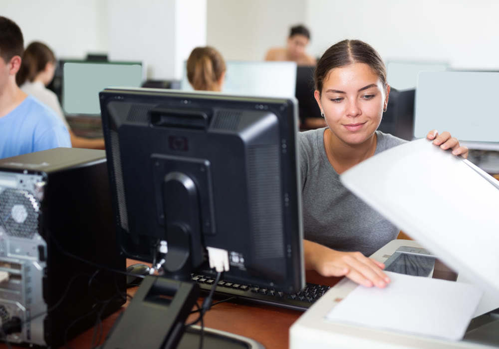 Female teacher uses a scanner in computer lab at school
