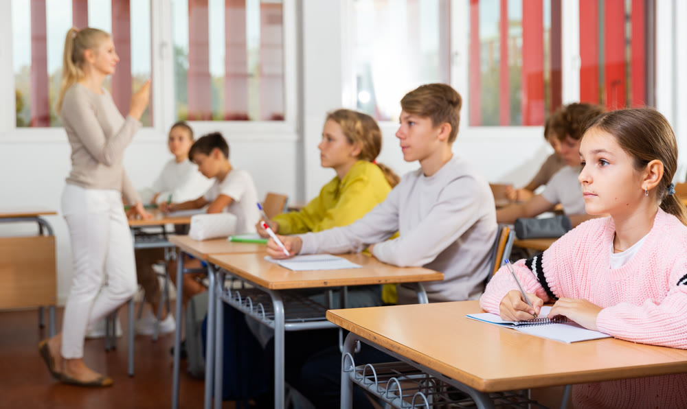 Teenagers sitting at desks in classroom during lesson