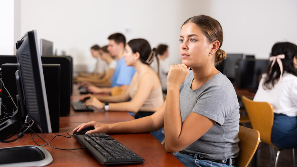 Teacher works at computer in the classroom. Students doing programming