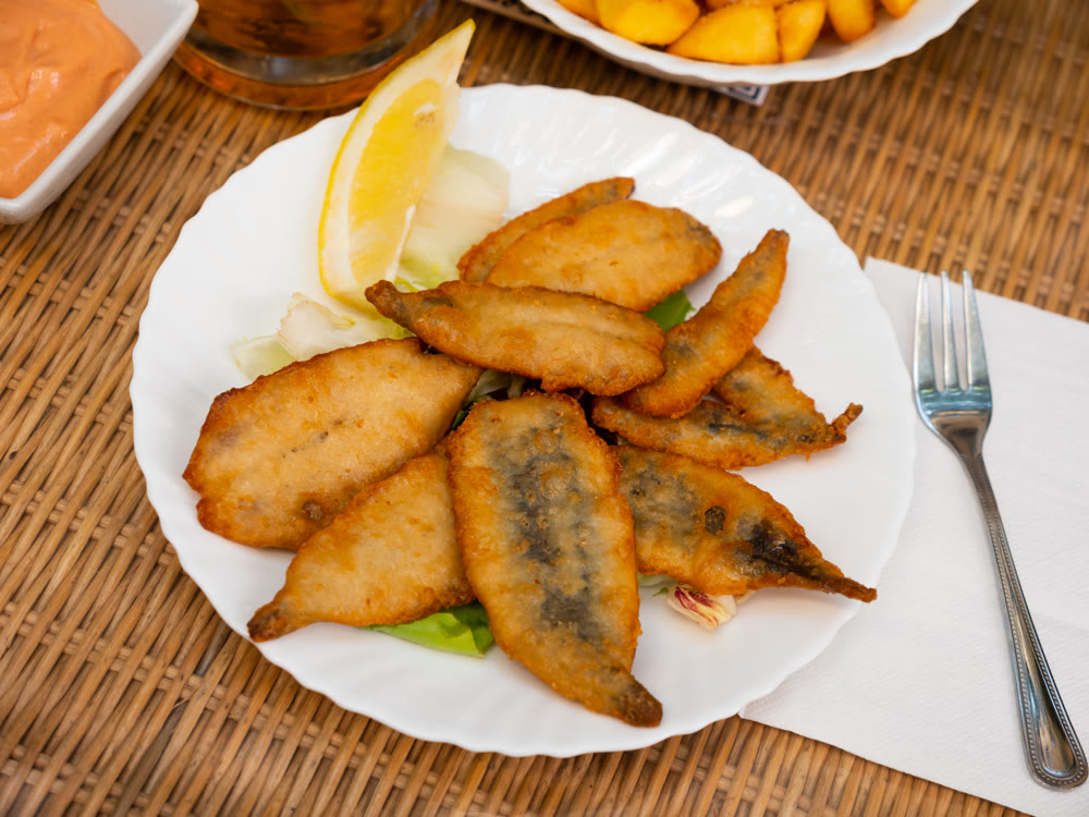 Pan-fried battered served on plate with vegetables and lemon