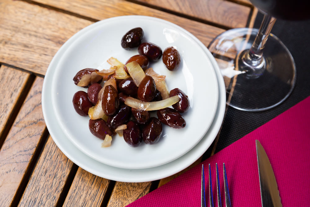 Pickled whole olives with pits and onions in bowl on the table
