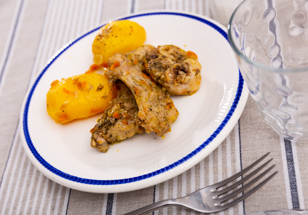 Grilled rabbit leg quarters served on plate with boiled potatoes closeup