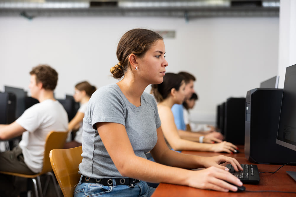Side view on diligent college girl studying using pc in computer class