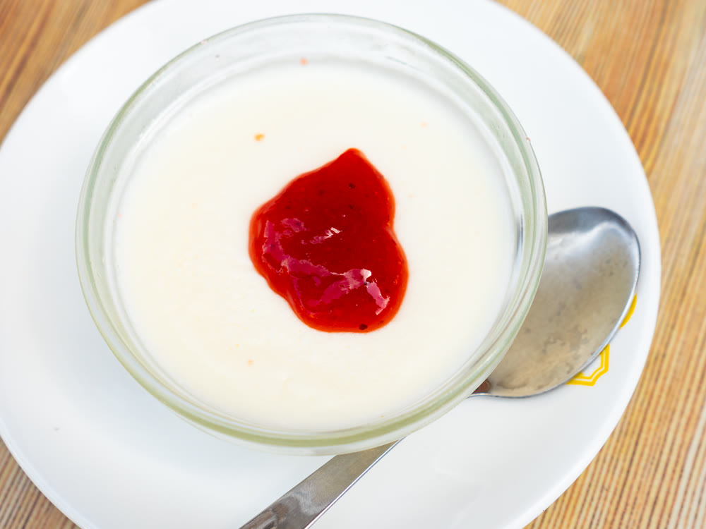 Creamy panna cotta with cranberry jam in glass bowl
