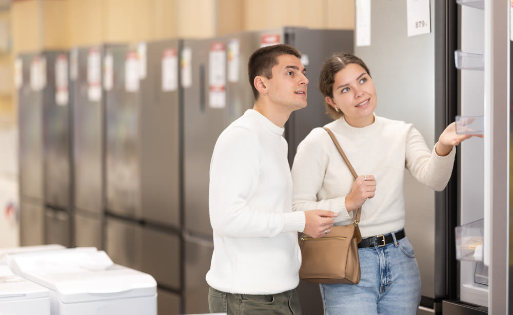 Young couple choosing refrigerator in appliance store