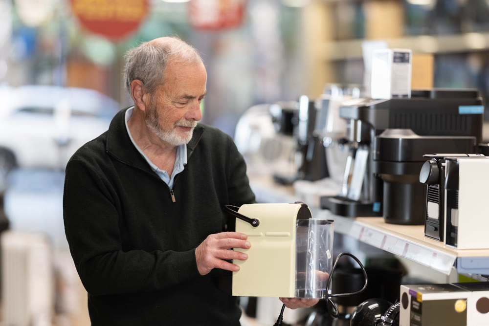 Elderly man chooses coffee machine in hypermarket