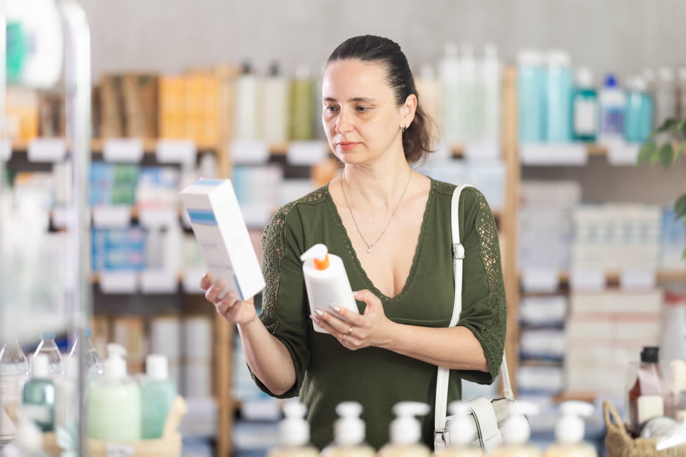 Middle-aged woman customer choosing cream in drugstore