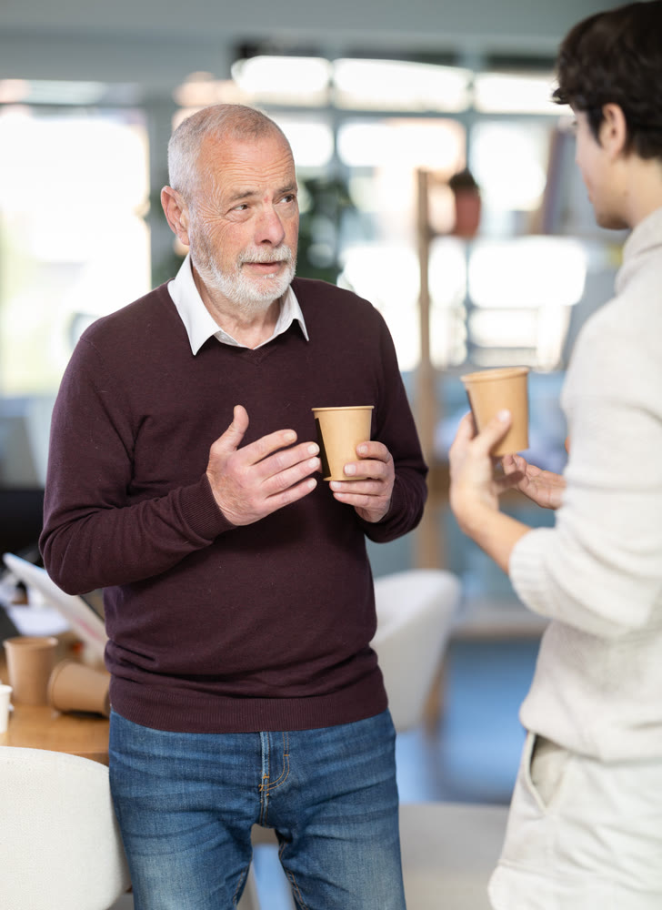 Two office workers drink coffee and chat during work break