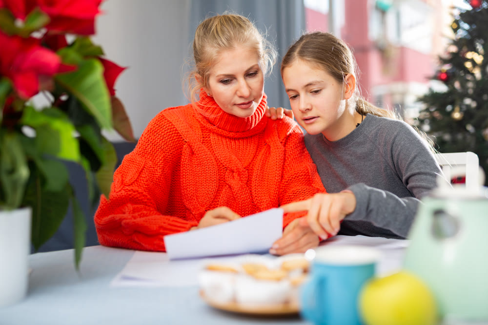 Mom together with daughter write a congratulatory letter during christmas time